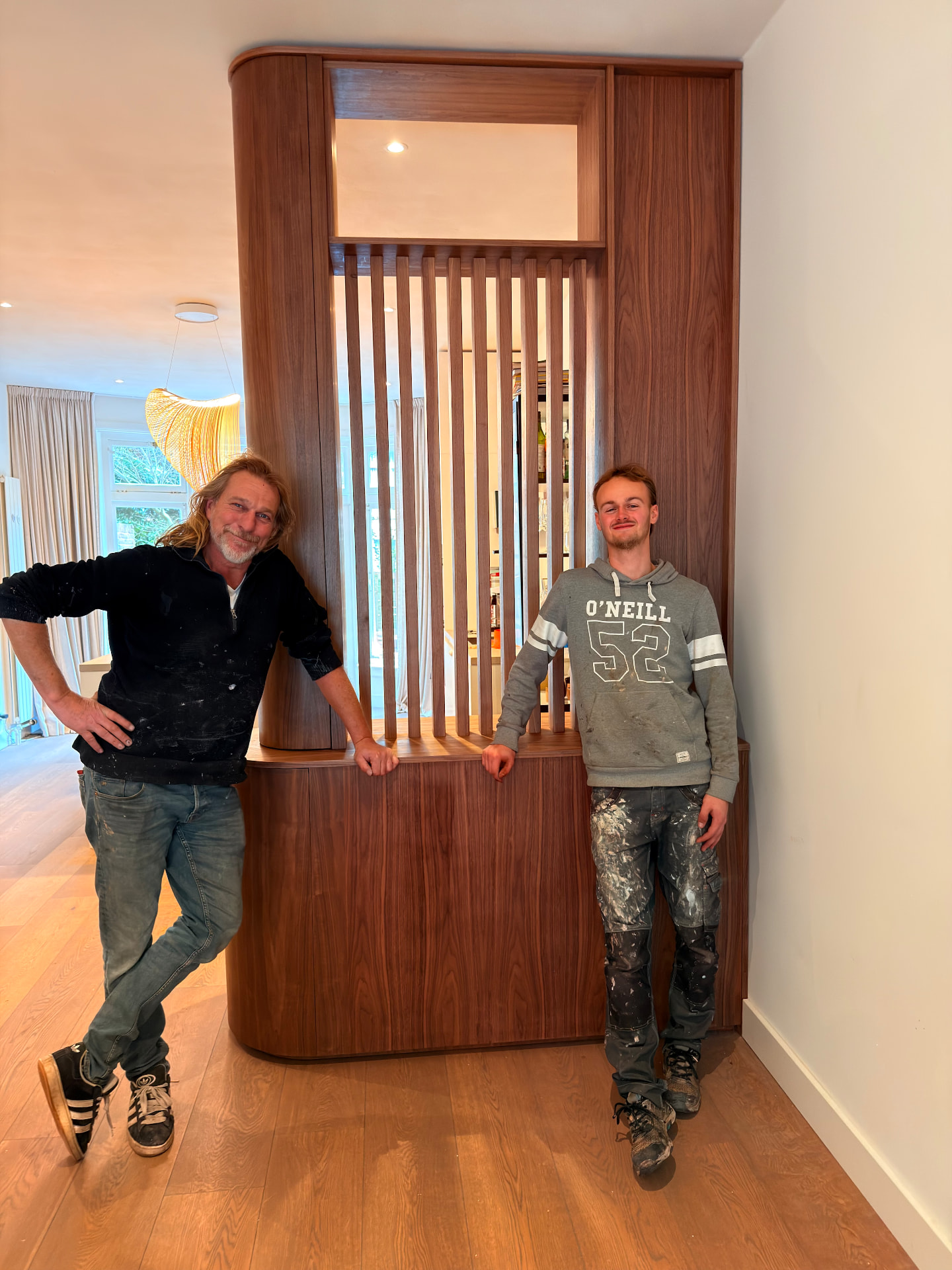 Twee makers naast een walnoten roomdivider in een woonkamer